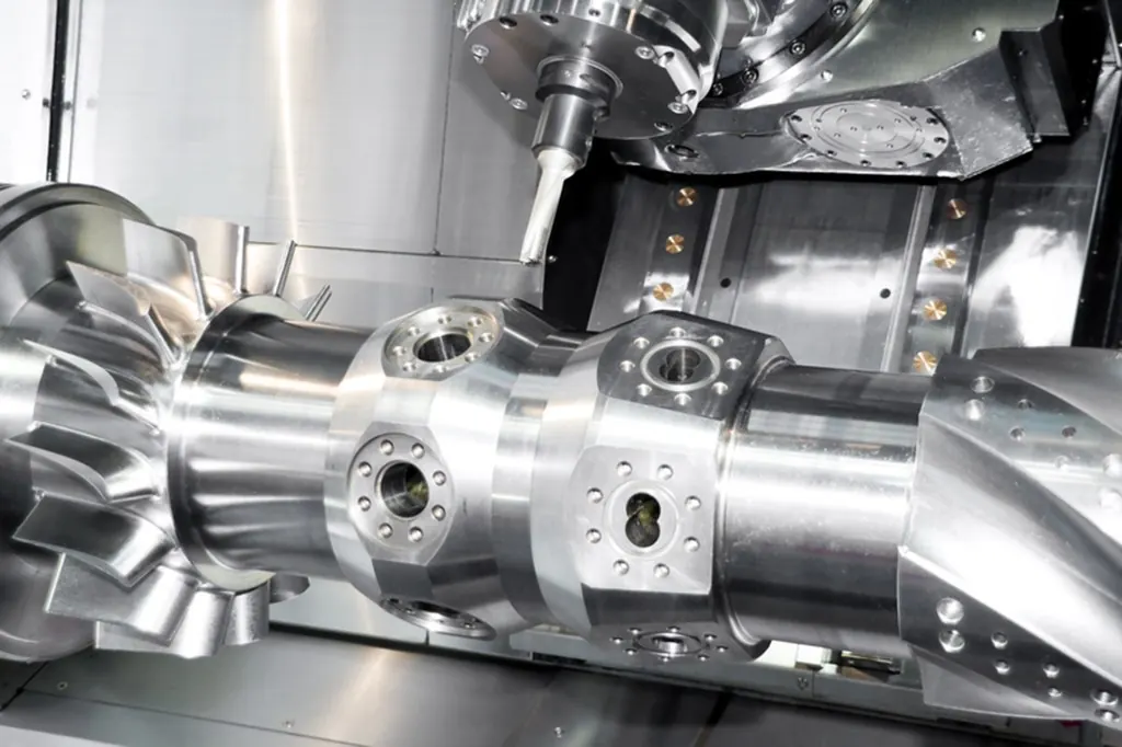 Centro de usinagem CNC trabalhando uma peça metálica com iluminação industrial.